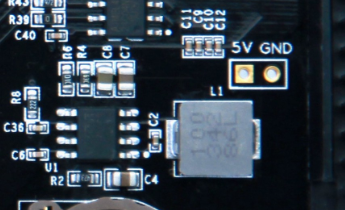 图片显示了扩展板上电源+5V电路的实物图，其中包含一个标有“1.0V 100Ω”的电阻器和一个标有“1.0V 100Ω”的电容器。此外，图片中还可见到一个标有“5V GND”的引脚和一个黄色的电容。这些元件在扩展板电源设计中起到关键作用，确保+5V电源的稳定输出。图片在上下文中用于直观展示电源电路的实物布局，帮助读者更好地理解电源设计的具体实现。