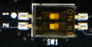 图片展示了AX7Z100开发板上核心板上的拨码开关SW1。开关上有“ON”和“OFF”两个位置，其中“ON”位置对应1、2位置，且MIO5、MIO4电平为0、0，启动模式为JTAG；“OFF”位置对应1、2位置，MIO5、MIO4电平为1、1，启动模式为SD卡；“OFF”位置对应1位置，MIO5、MIO4电平为1、0，启动模式为QSPI FLASH。该图片与文档中介绍拨码开关SW1启动模式配置的内容相呼应，直观呈现了开关各位置对应的状态及启动模式。