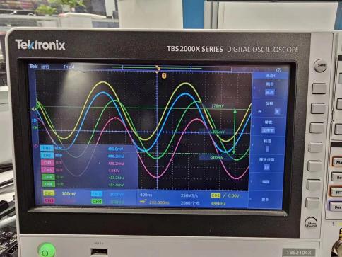图片显示了一台Tektronix TBS2000X系列数字示波器的屏幕，屏幕上展示了四条不同颜色的波形曲线，分别标记为CH1、CH2、CH3和CH4。波形曲线的参数如电压、频率和偏移量等在屏幕下方的参数框中清晰显示。图片在上下文中用于展示黑金AXP110开发板FMC接口和FL9781的硬件连接图，通过在示波器中观察DA输出的正弦波形，验证硬件连接的正确性。